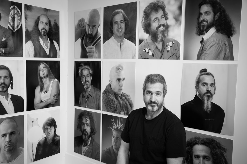 Black and white photography in Richmond, VA, of a man in front of a portrait wall.
